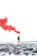 selective color photography of person holding orange gas smoke standing on snow