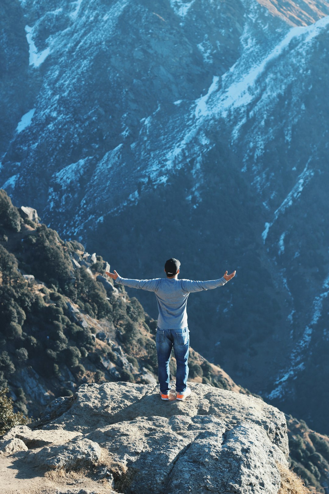 person standing on rock mountain while raising his hand sideways