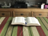 An open book with a pen on a wooden table.