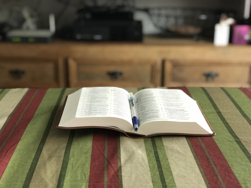 photo of blue ballpoint pen on opened book