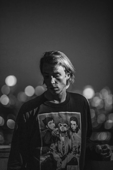 A cozy black and white photo of a model wearing a soft oversized cotton combed 24s t-shirt in a casual 90s style setting.