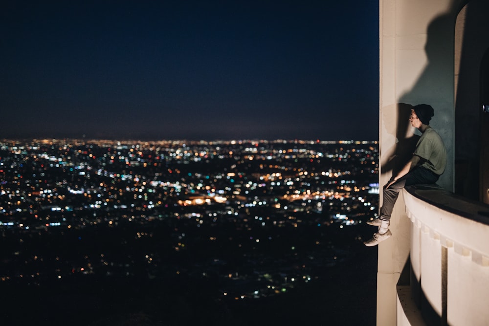 man sitting on building balcony during nighttime