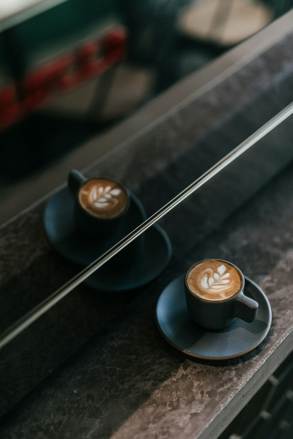 Schwarze Keramiktasse mit Cappuccino-Kaffee mit Blattschaum auf dem Tisch