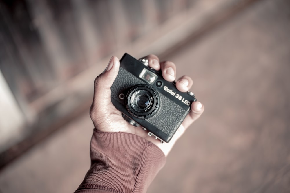 person holding black and gray point-and-shoot camera