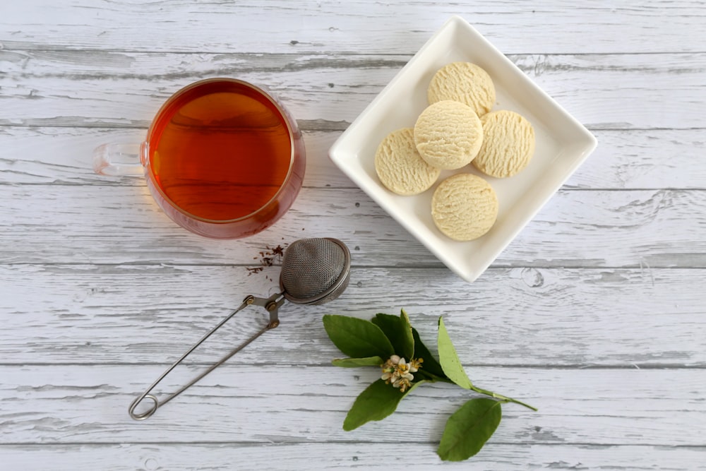 prato de biscoitos e copo de vidro cheio de líquido vermelho