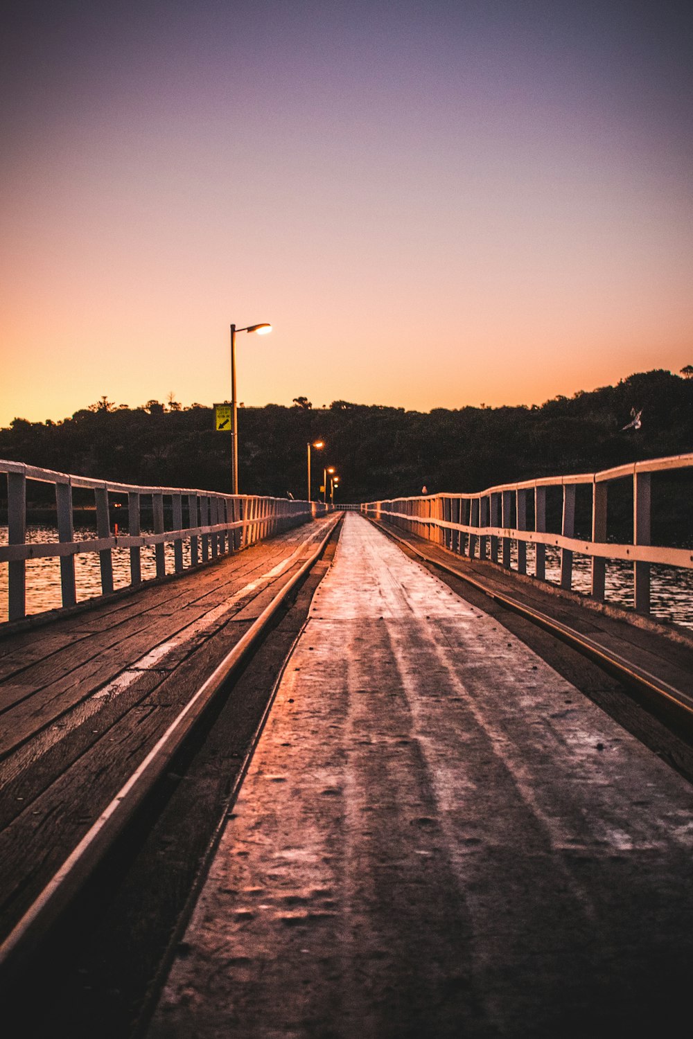 photo of brown and grey wooden beach dock near hill under clear blue sky