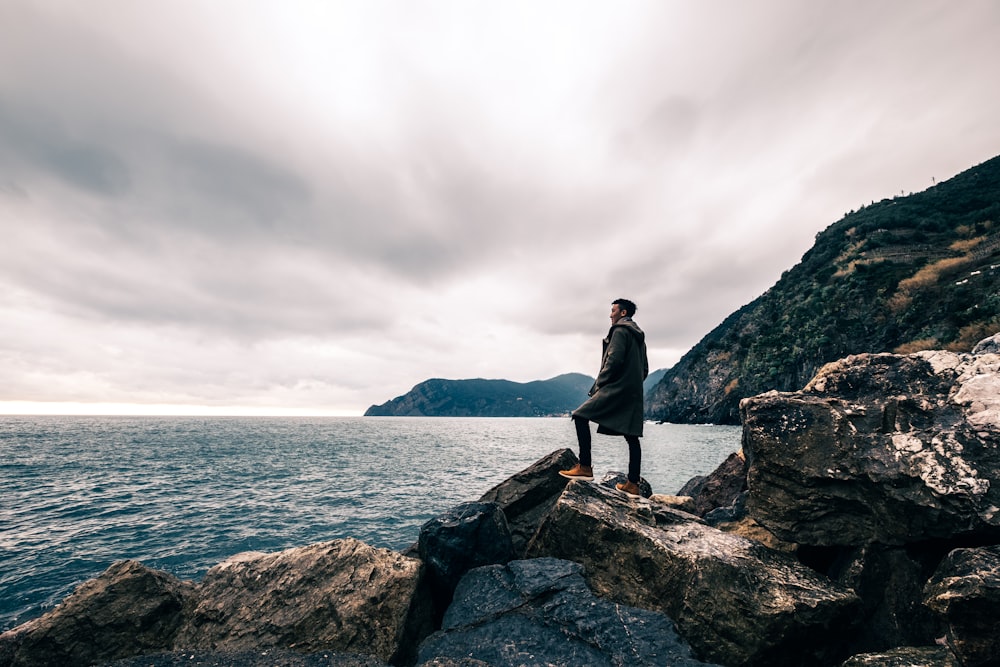 uomo in piedi sul masso vicino allo specchio d'acqua