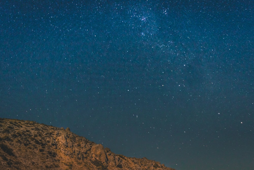 brown mountain under blue and gray sky with stars