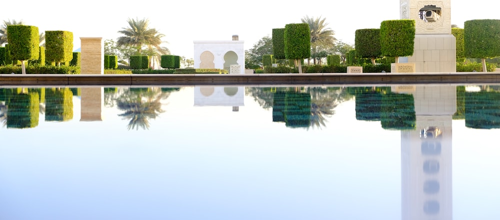 white concrete structure and trees reflected on water during daytime