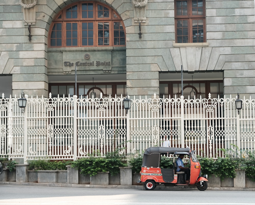 Rickshaw rojo estacionado frente a una estructura de concreto