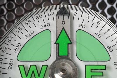 a close up of a compass with a green arrow