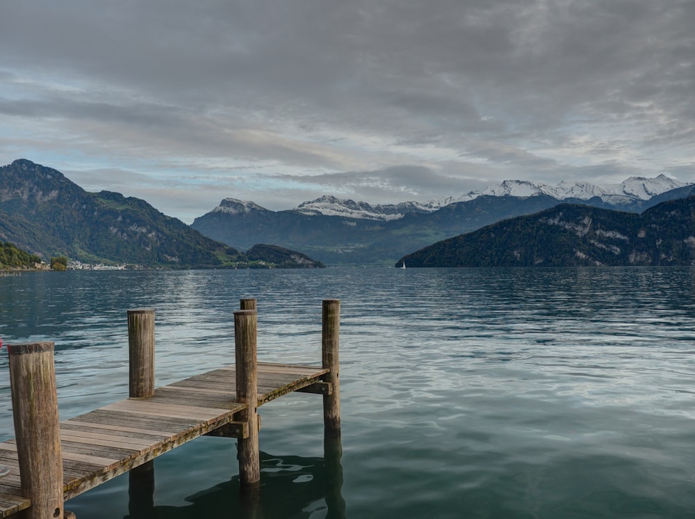 closeup photo of brown wooden dock facing mountain and calm body of water