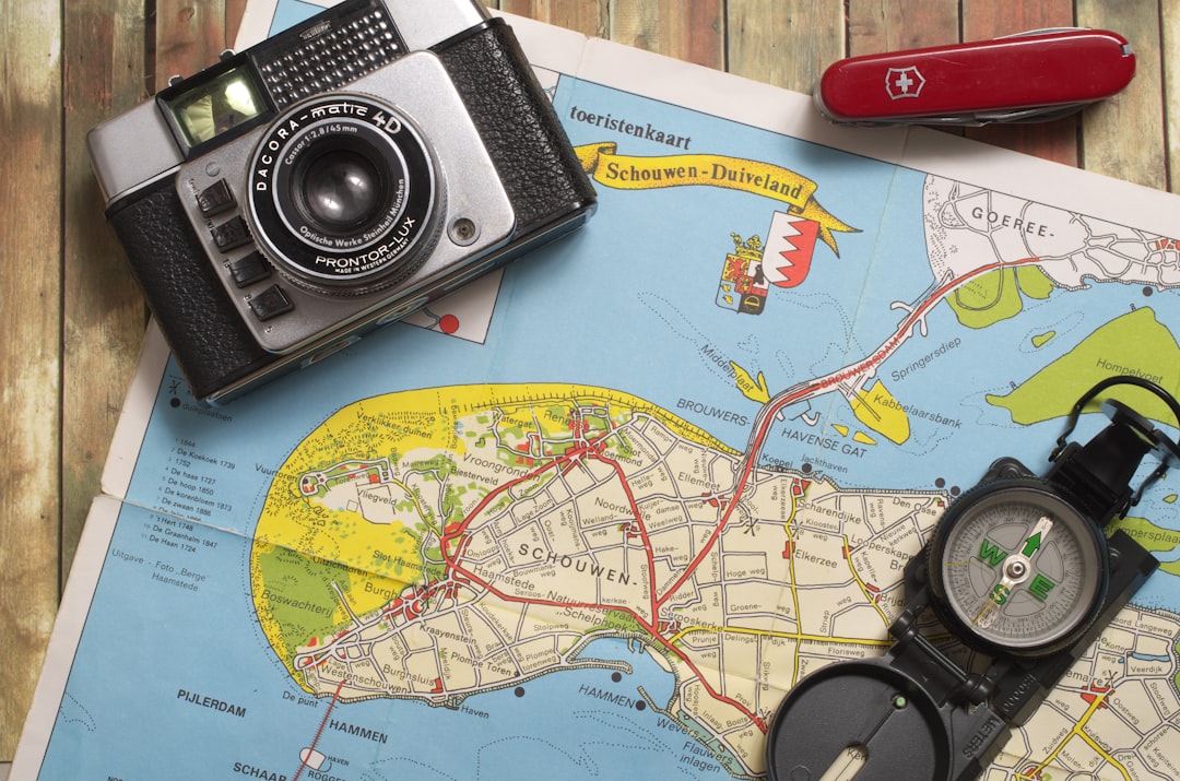 black and gray camera on blue world map, island-map on wooden floor