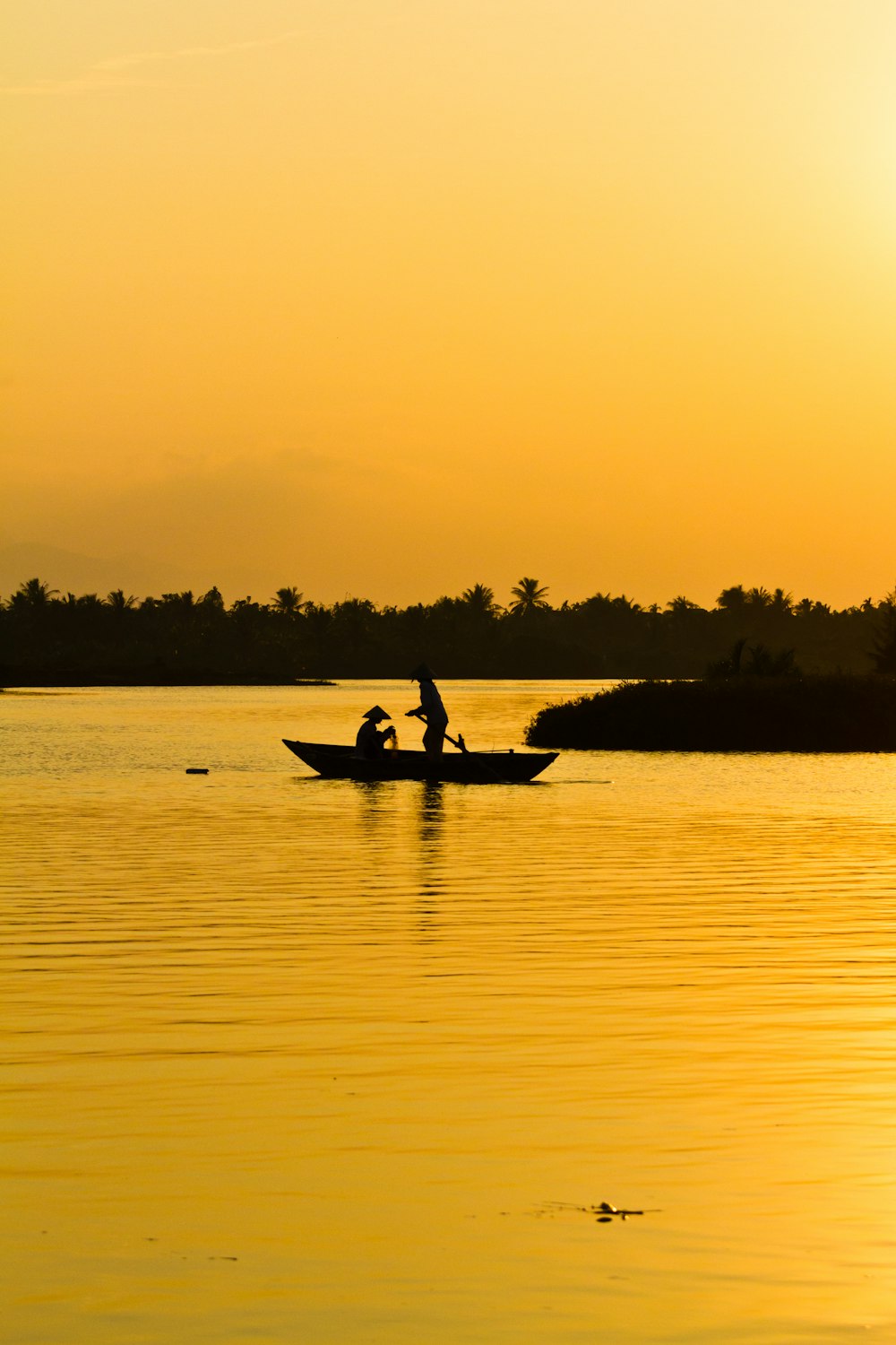 photography of silhouette of two person's in sitting and standing in boat