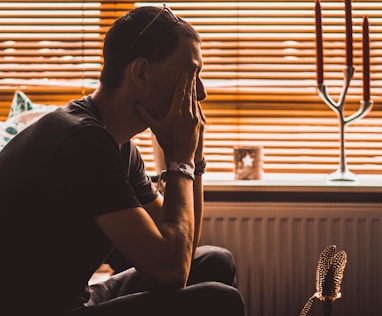 man sitting on chair covering his eyes stressed over creating social media content