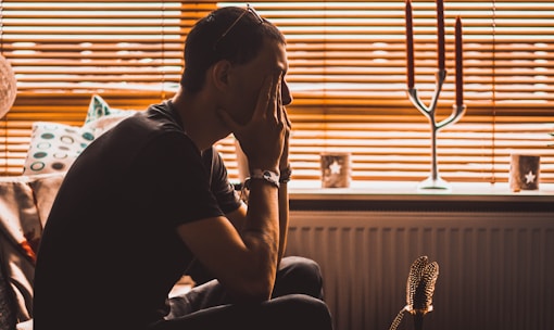 tired man sitting on chair covering his eyes