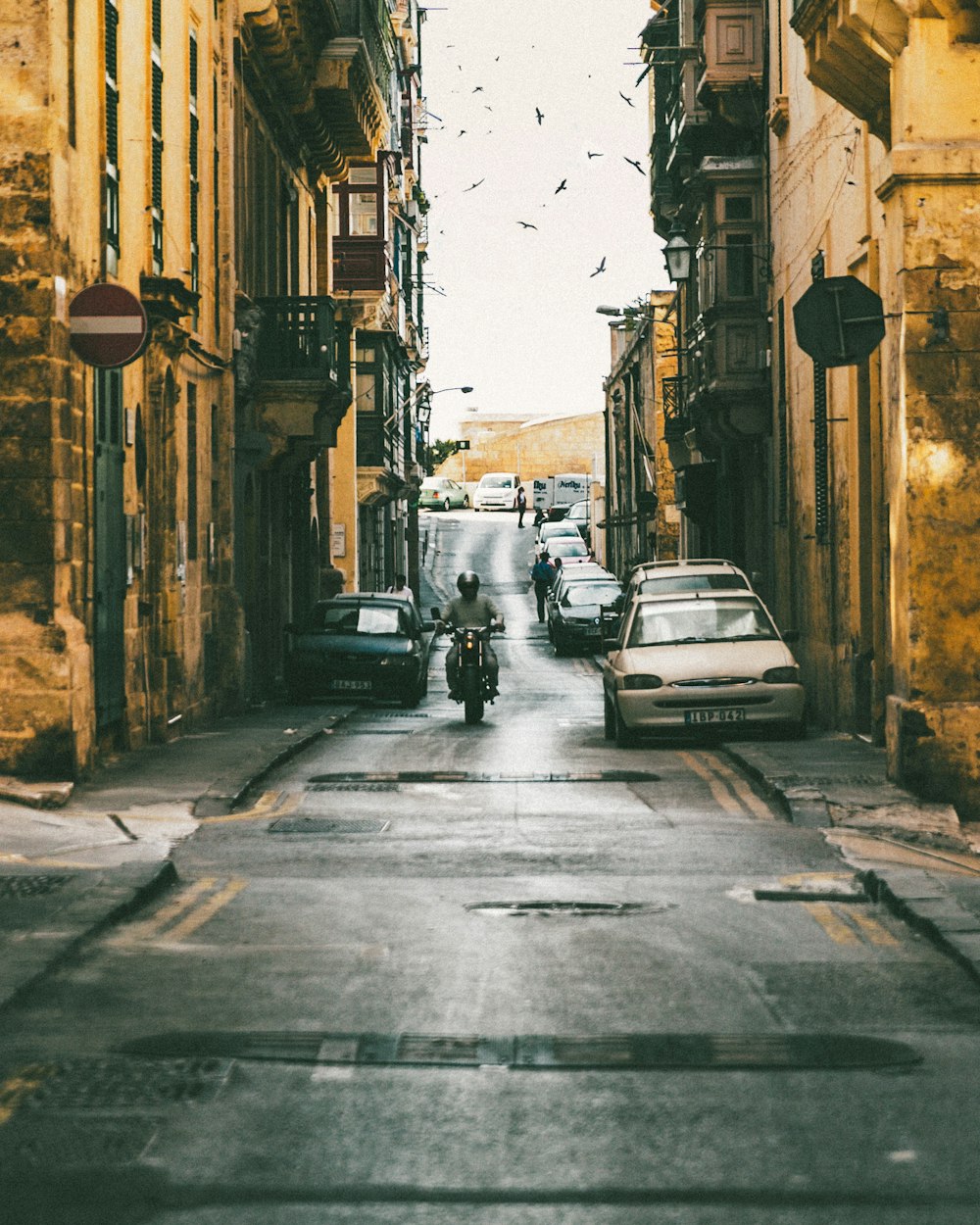 man riding motorcycle passing through buildings