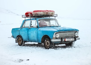 blue sedan on snow ground