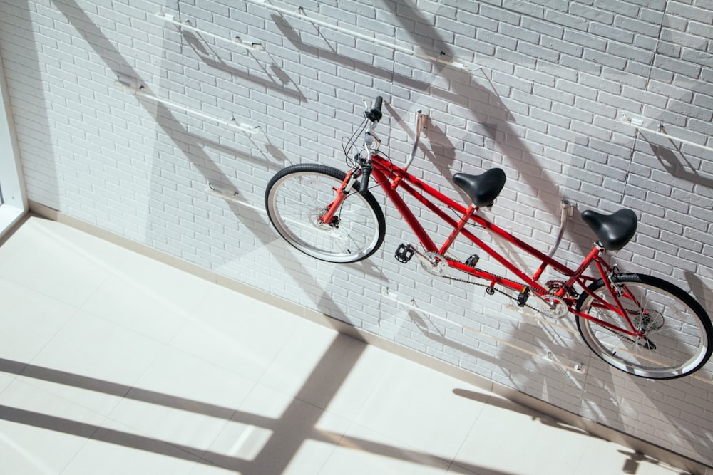 Bicicleta tándem roja colgada en la pared