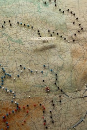 A vintage map of Czechoslovakia containing pushpins in various colors such as red, blue, white, and black, marking different locations across the region. The map displays various place names, rivers, and topographical features.