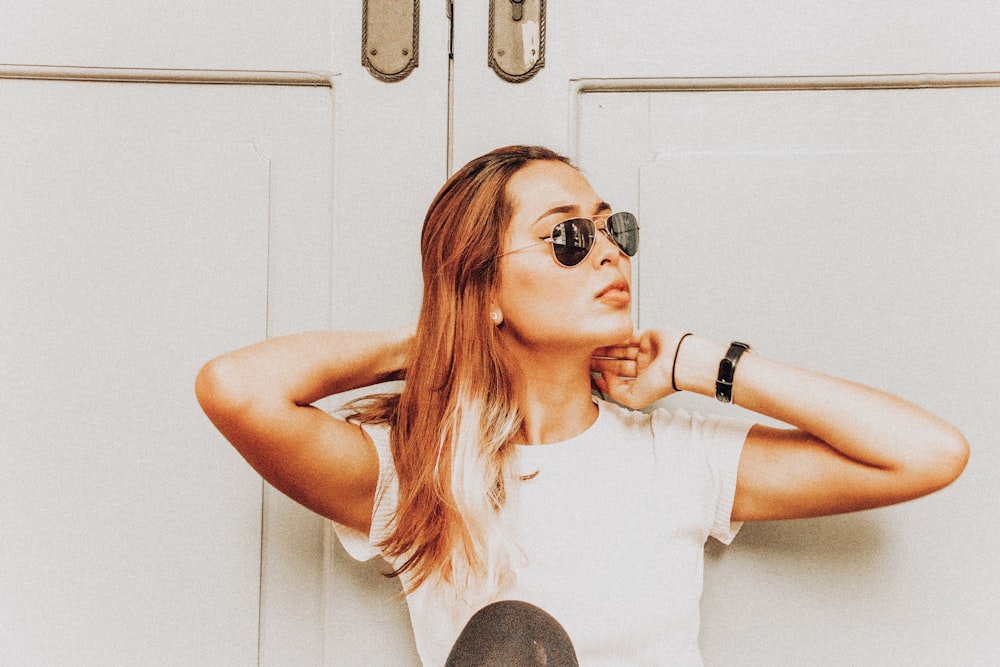 woman wearing black sunglasses standing in front of door at daytime