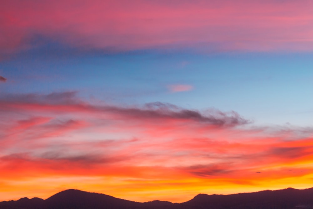 silhueta da montanha sob o céu azul nublado foto tirada durante o pôr do sol
