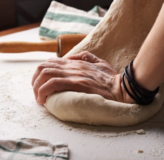 person making dough beside brown wooden rolling pin