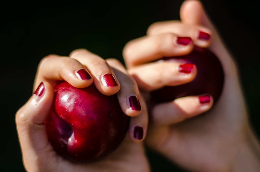 selective focus photography of person holding red apples