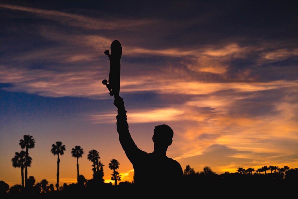 silhouette of man holding skateboard