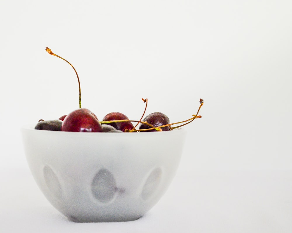 red cherries in white ceramic bowl