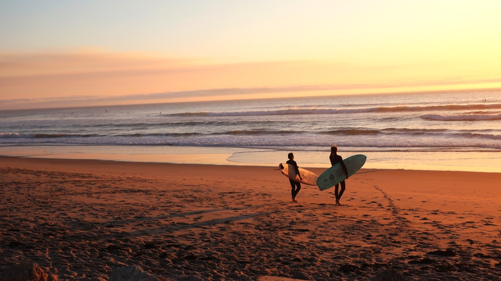 two surfers walking on sand going on water