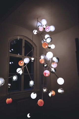An electrician installing a chandelier in a modern living room.
