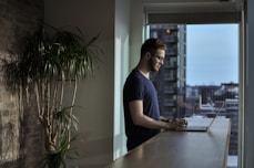 man standing beside table using laptop