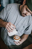 Barista carefully pouring latte art into a fresh cup of coffee.