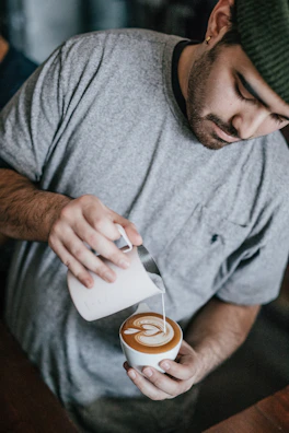 Barista carefully pouring latte art into a fresh cup of coffee.