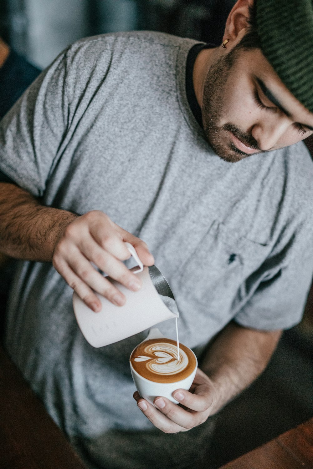 homme en T-shirt à col rond gris faisant du cappuccino