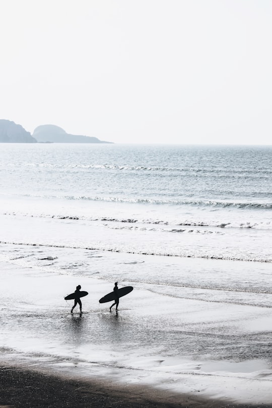 two people carrying surfboards at beach during daytime in Salinas Spain