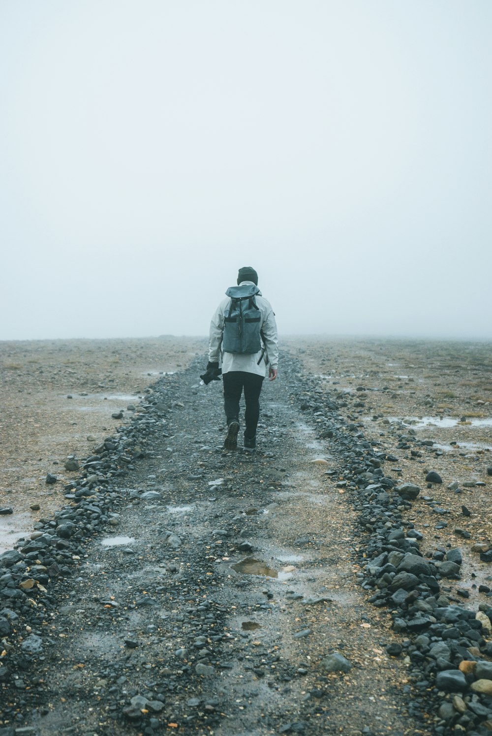 man with backpack walking on brown field