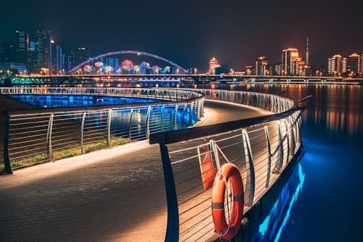 curve road with railings near buildings with lights at night