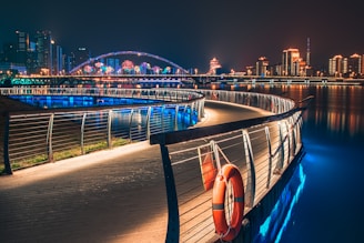 curve road with railings near buildings with lights at night