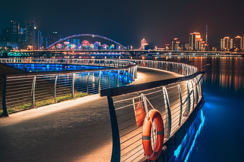 Carretera curva con barandillas cerca de edificios con luces por la noche