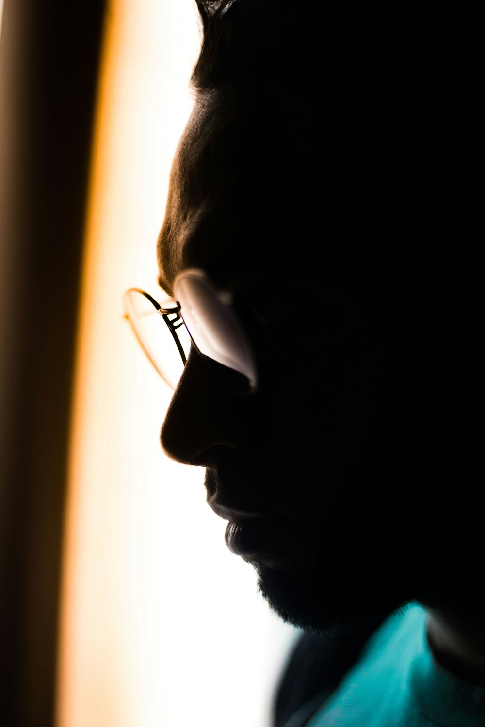 man wearing eyeglasses and teal crew-neck tops in close-up photography