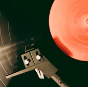 A close-up of a vintage turntable spinning with hip-hop vinyl records partially visible.