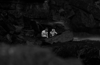 a couple of men sitting on top of a rock