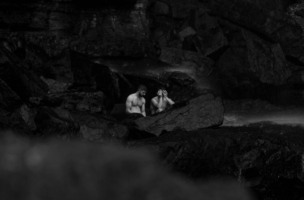 a couple of men sitting on top of a rock