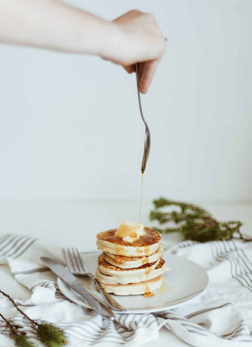 person pouring honey on top of pancake