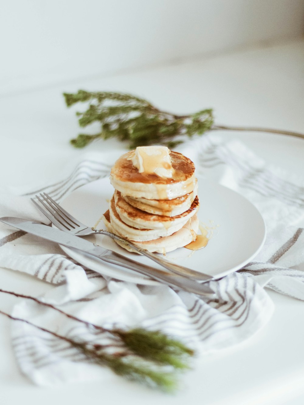 cooked pancake on round white ceramic plate beside butter knife and fork