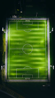 A close-up shot of a soccer field with players mid-action under stadium lights.