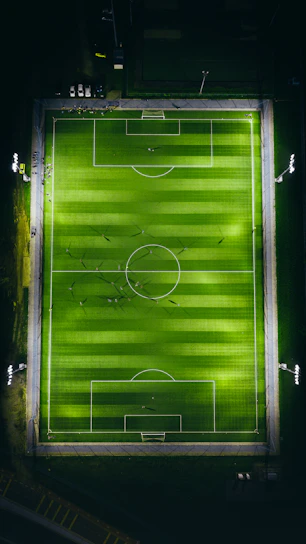 A close-up shot of a soccer field with players mid-action under stadium lights.