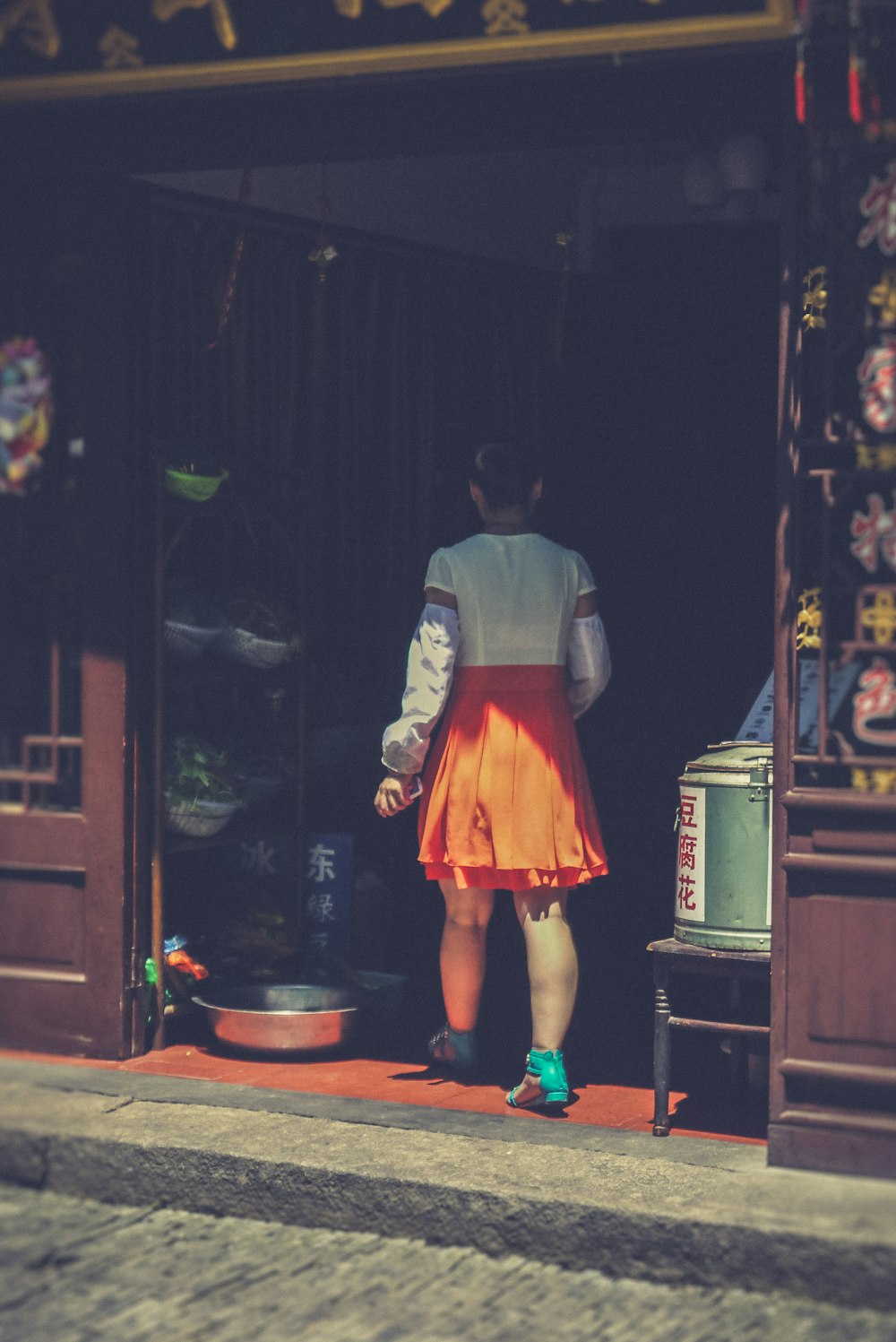 woman wearing white top and orange skirt walking in store